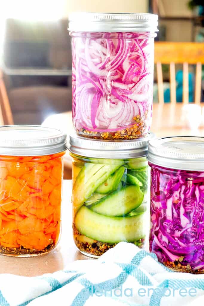 Quick Pickles in mason jars—Quick pickled red onions, quick pickled cucumbers, quick pickled carrots and quick pickled cabbage.